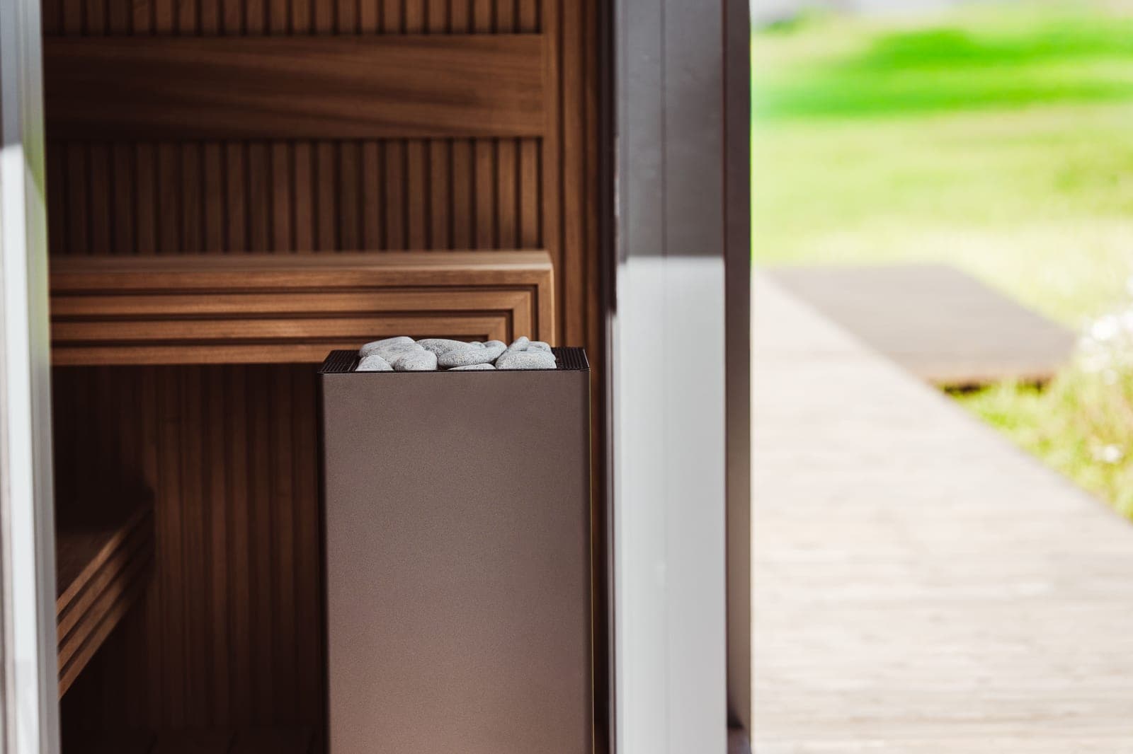 The wooden interior of a small home sauna, lit by plain daylight